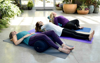 Women in Savasana on Round Bolster - Blue, Junior Bolster - Celery, Standard Bolster - Indigo Ikat
