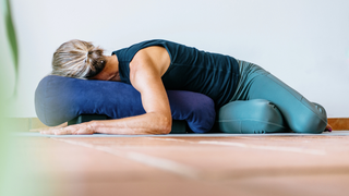 Woman lying in a belly-down twist on a bolster