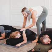 Teacher Helping Student in Restorative Twist on Standard Yoga Bolster - Black