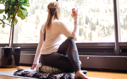 Woman in Ardha Matsyendrasana (Seated Twist) on Zafu - Wild Sky
